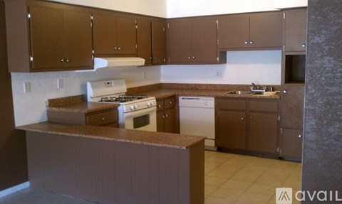 A kitchen with brown cabinets and a white stove top oven.