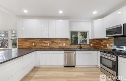 A modern kitchen with white cabinets and a wooden backsplash.