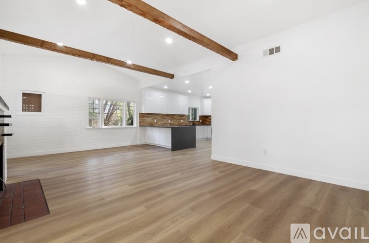 A spacious room with wooden floors and white walls.