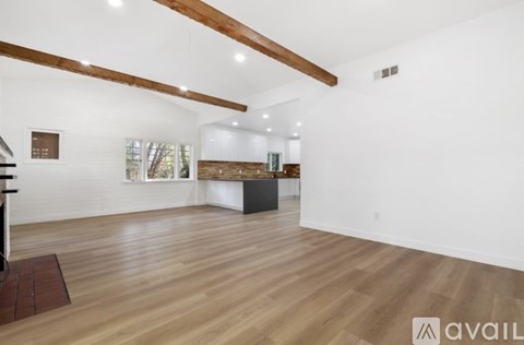 A spacious room with wooden floors and white walls.