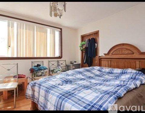 A bedroom with a bed covered in a blue and white plaid comforter.