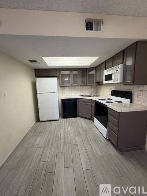 A kitchen with a white fridge, black stove, and brown cabinets.