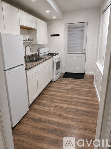 A kitchen with white appliances and wooden floors.