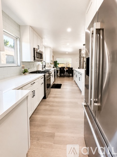 A modern kitchen with a stainless steel refrigerator and white cabinets.