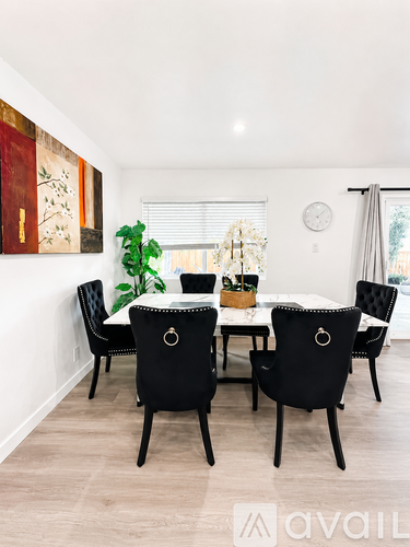 A dining room with a table surrounded by chairs.