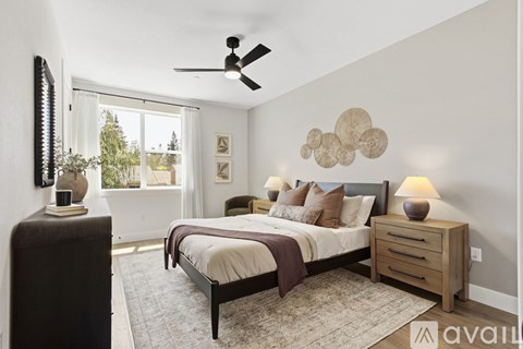 A bedroom with a bed, nightstand, and a ceiling fan.