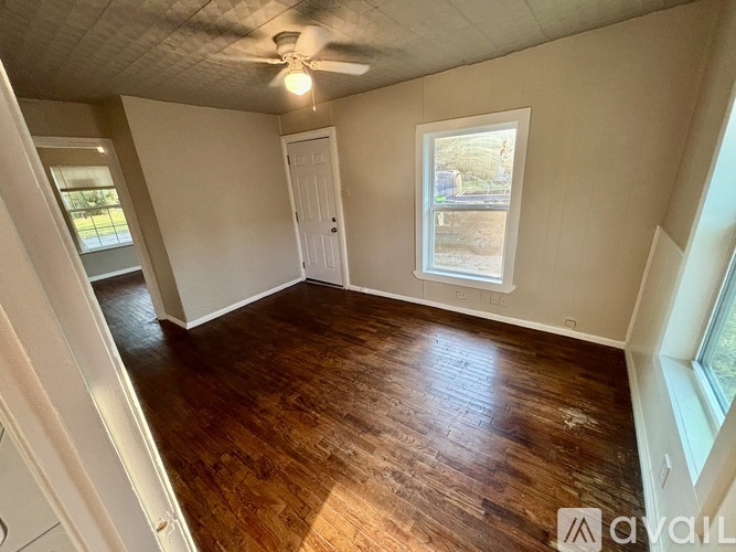 A room with wooden flooring and a window showing a view of a street.