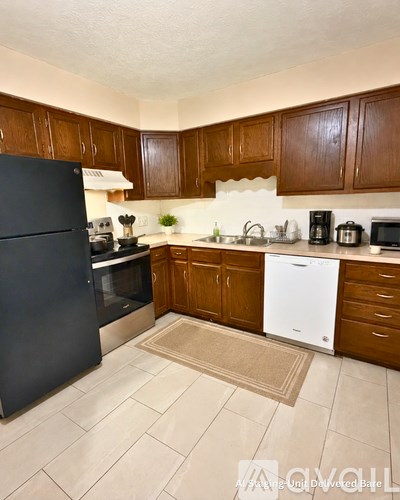 A kitchen with brown cabinets and a black refrigerator.