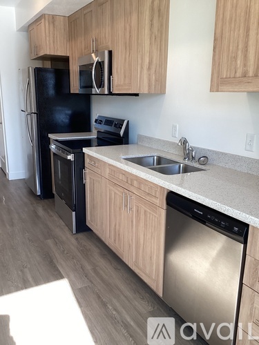 A kitchen with a black fridge and stove, wooden cabinets, and a white sink.