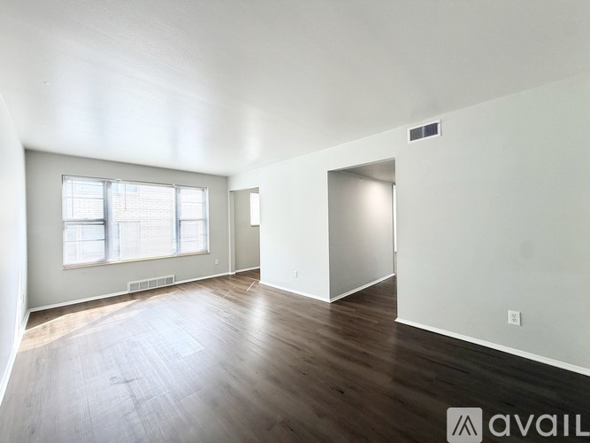 A spacious room with wooden flooring and a window.