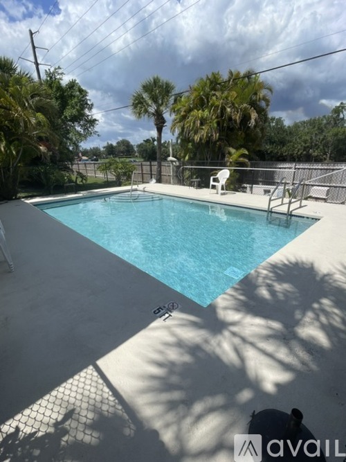 A pool surrounded by a fence and palm trees.