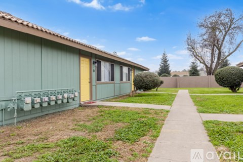 A green building with a yellow door and a walkway in front.