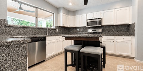 A kitchen with white cabinets and a granite countertop.