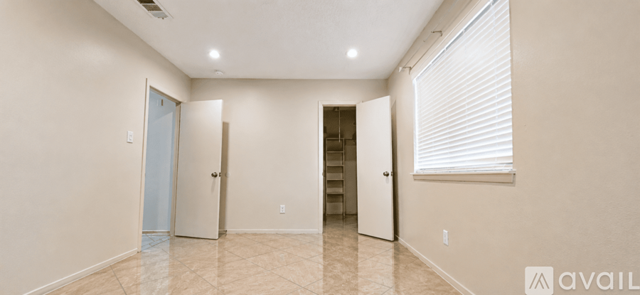 A spacious room with a tiled floor and a window with blinds.