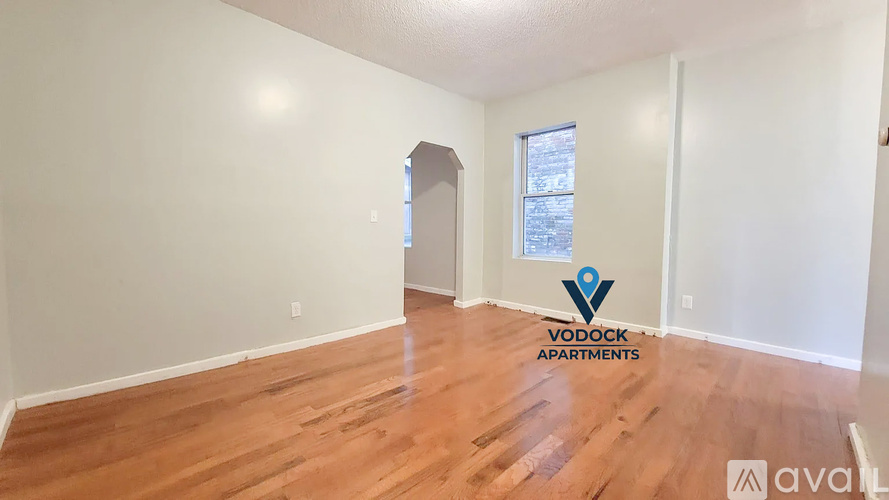 A room with wooden flooring and a window with a view of a building outside.