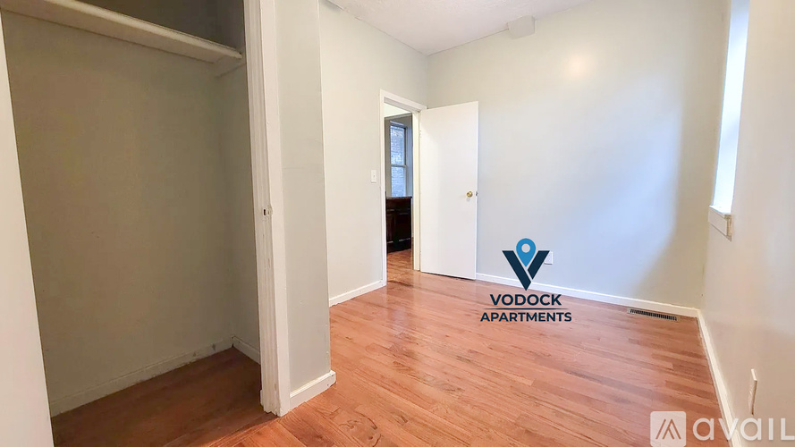 A room with wooden flooring and a logo of Vodock Apartments on the wall.