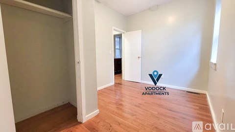 A room with wooden flooring and a logo of Vodock Apartments on the wall.