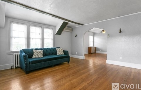 A living room with a blue couch and wooden floors.