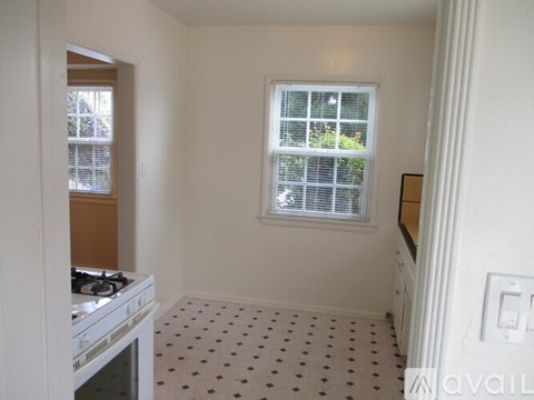 A kitchen with a white stove and a window with blinds.