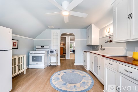 A kitchen with white cabinets and a blue rug on the floor.