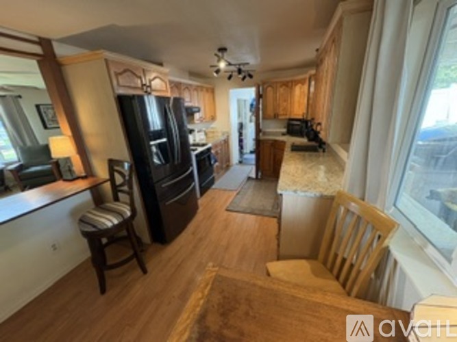 A kitchen with wooden floors and a black refrigerator.