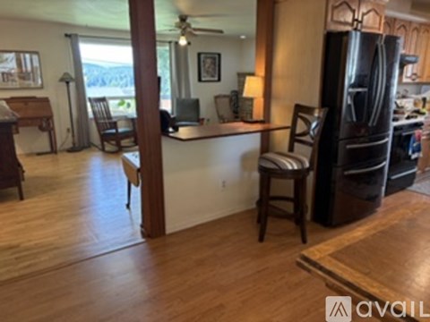 A kitchen with a refrigerator, a dining table with chairs, and a counter with a lamp.