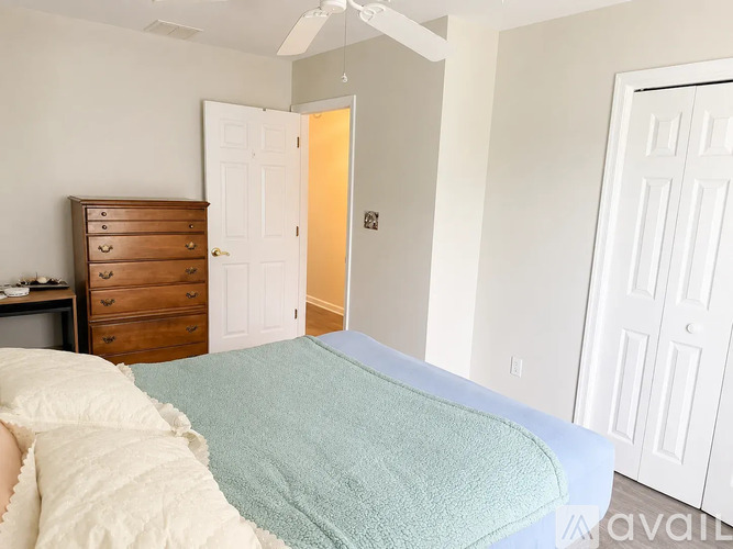 A bedroom with a bed, dresser, and two doors.