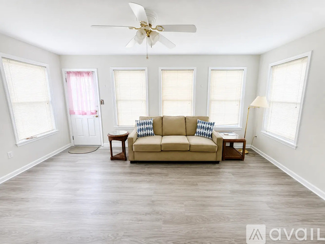 A living room with a beige couch and a ceiling fan.