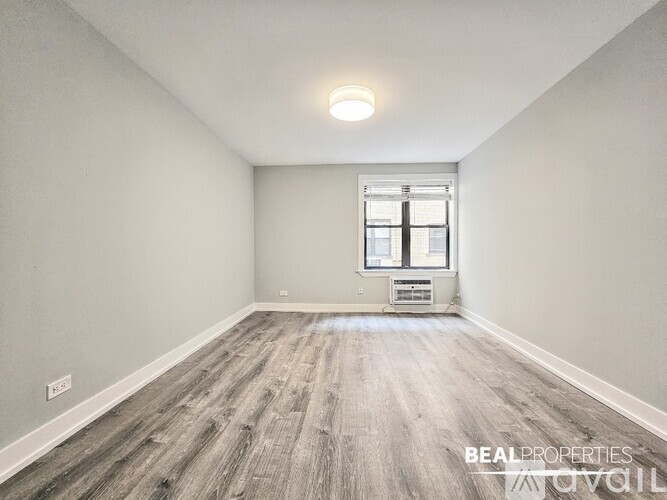 A spacious room with a window and a wooden floor.