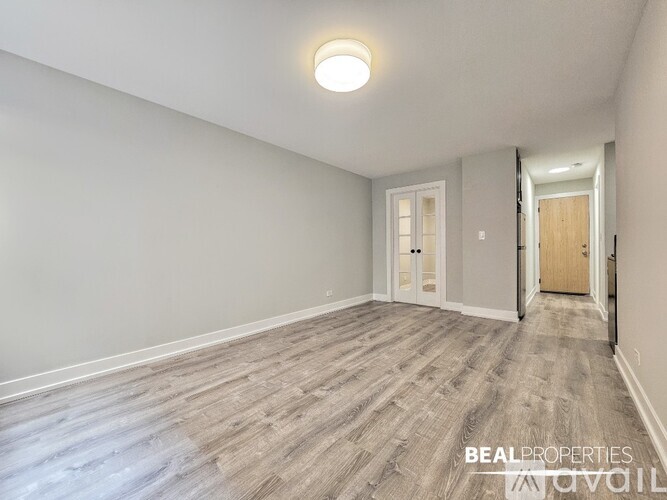 A spacious room with wooden flooring and white walls.