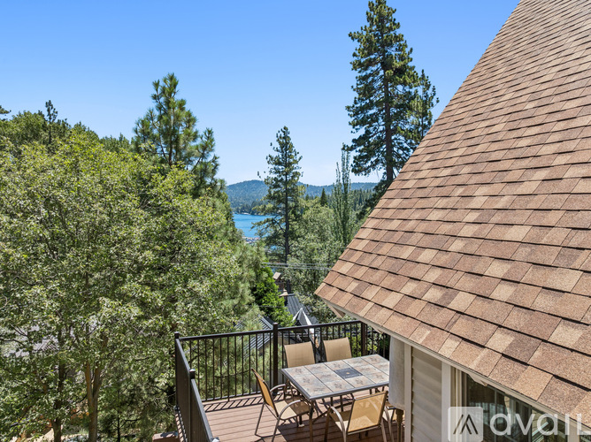 A patio with a table and chairs overlooks a lake and trees.