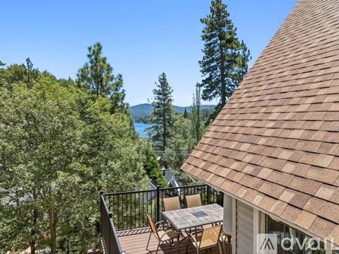 A patio with a table and chairs overlooks a lake and trees.