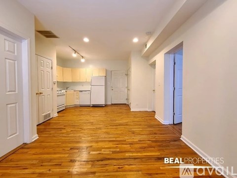 A spacious kitchen with wooden floors and white walls.