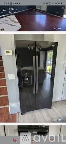 A black refrigerator with a white handle is in a kitchen.