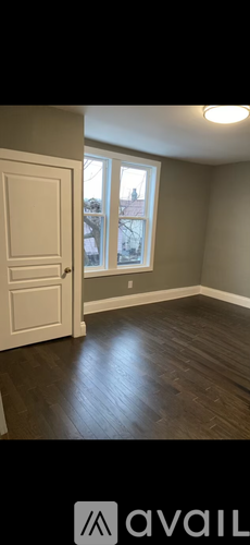 A room with a white door and a window with a view of a building outside.
