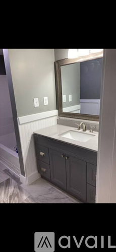 A bathroom with a sink, mirror, and cabinets.