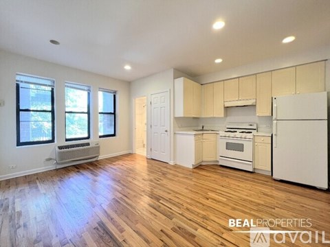 A spacious kitchen with white appliances and wooden floors.