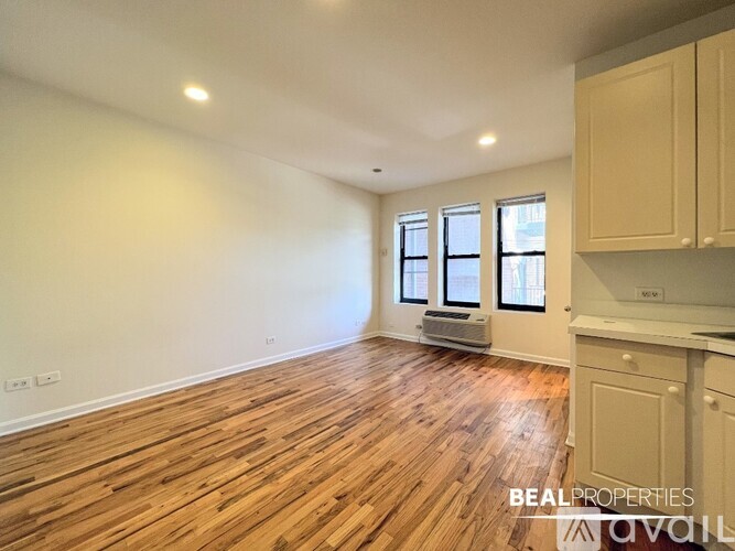 A spacious room with wooden flooring and a window with blinds.
