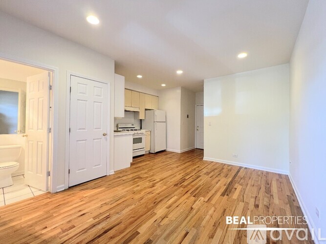 A spacious room with wooden flooring and white walls.