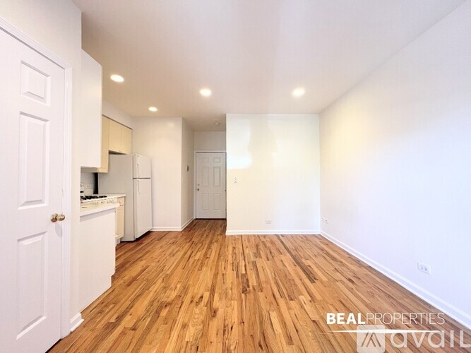 A spacious room with wooden flooring and white walls.