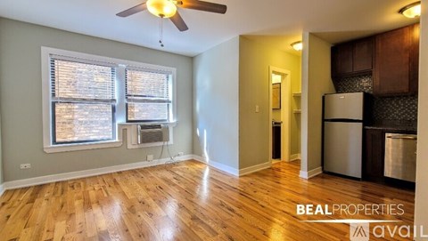 A BEALPROPERTIES AVAIL sign is on a wall in a room with wood floors and a ceiling fan.
