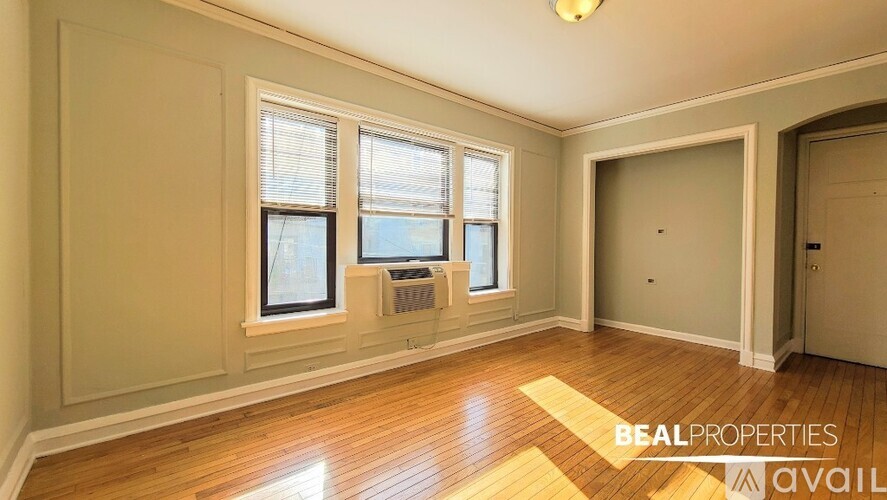 A room with wooden floors and two windows is available for rent.