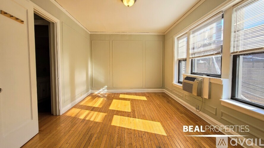 A room with wooden flooring and a window with blinds.