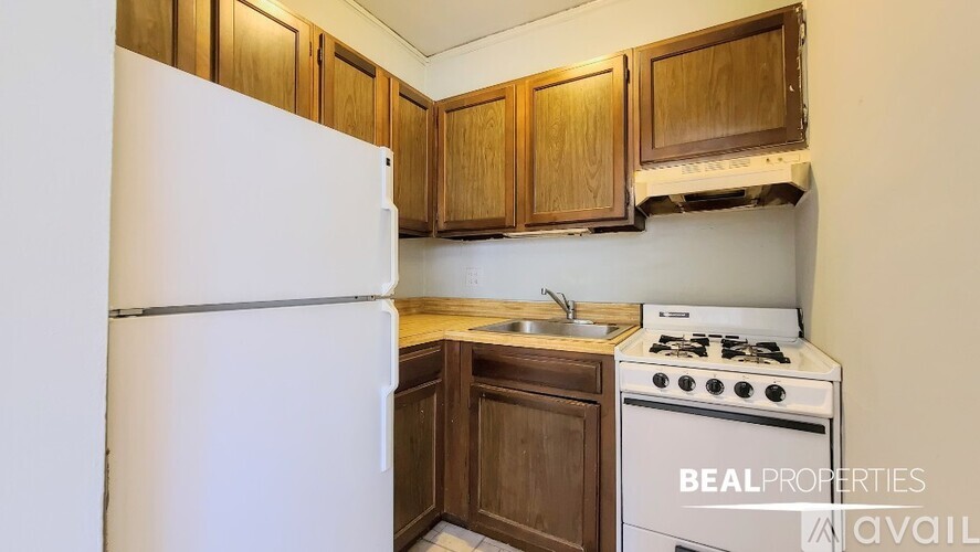 A kitchen with a white refrigerator, wooden cabinets, and a white stove top oven.