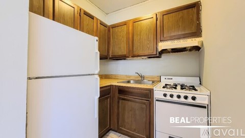 A kitchen with a white refrigerator, wooden cabinets, and a white stove top oven.