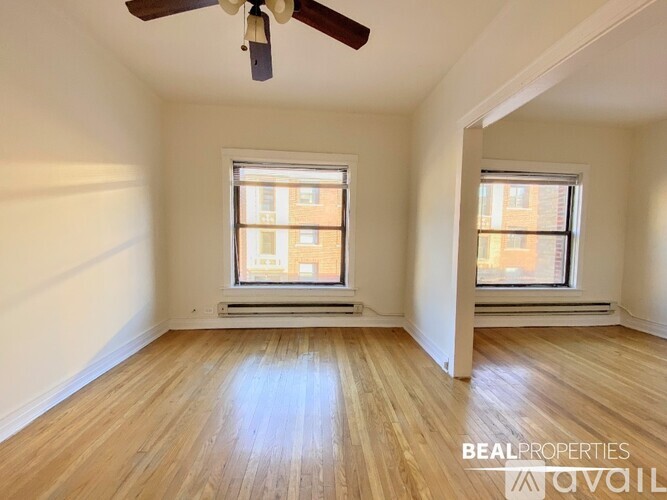 A room with a ceiling fan and two windows.