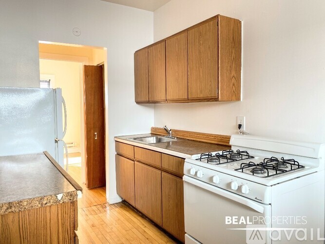 A kitchen with a white gas stove and wooden cabinets.
