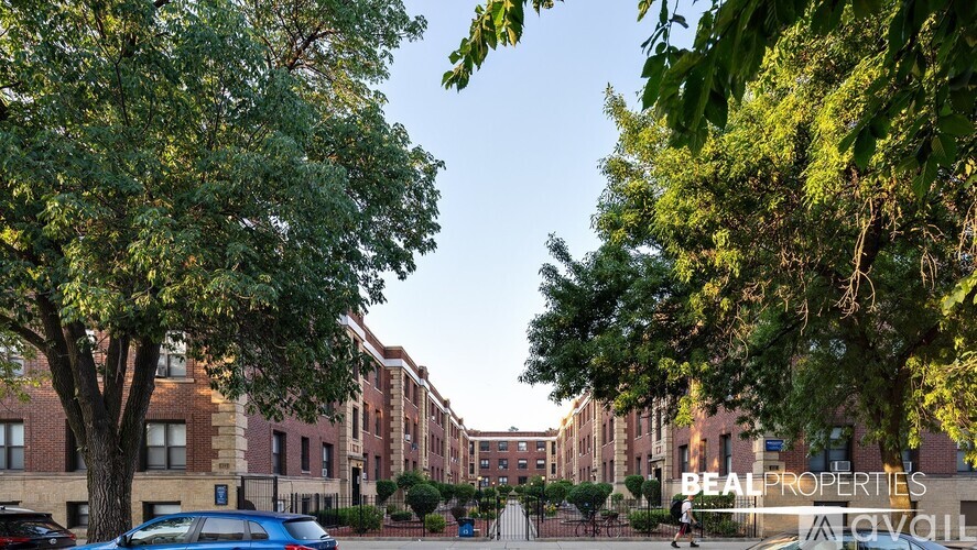 A blue car is parked on the left side of a tree in front of a brick building.