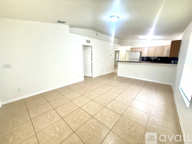 A spacious room with beige tiled flooring and white walls.
