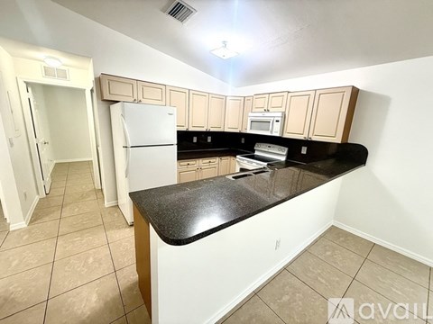 A kitchen with a black countertop and white appliances.